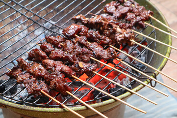 Satay goat satay, lamb, lamb or meat goat satay in grilling place with smoke by people with yummy looking.