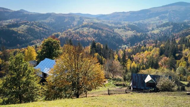 Ukraine, drone, flight in the Carpathians early in the autumn morning at sunrise near the city of Kosiv. Bright forests and dwellings of the Hutsul highlanders on the glades
