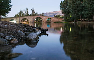 Ancient Romanesque bridge and river, village of Navaluenga in Spain