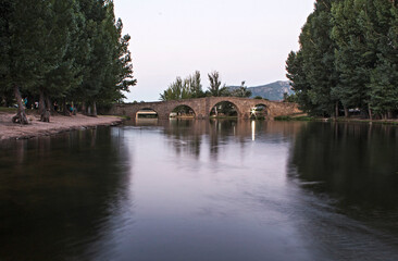 Ancient Romanesque bridge and river, village of Navaluenga in Spain