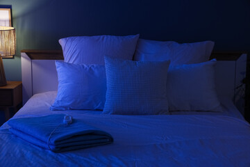 Folded electric heating pad on bed in dark room