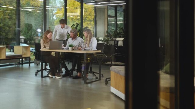 Creative business people, planning and meeting and brainstorming, ideas or strategy at office, view from glass wall.