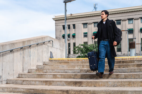 Man traveling down urban stairs with luggage