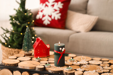 Burning candles with Christmas branches and snow on wooden table in living room