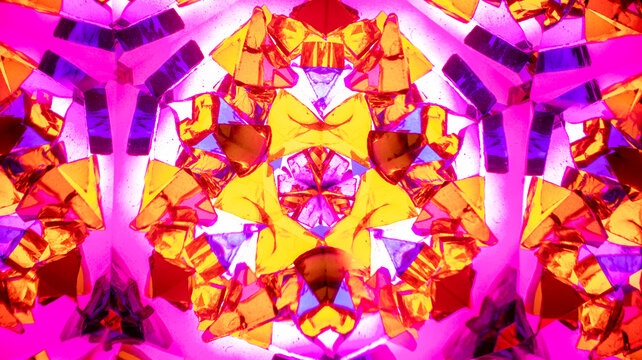 Natural macro kaleidoscope pattern photographed with a camera, showing vibrant abstract geometric shapes in pink, purple, and yellow.