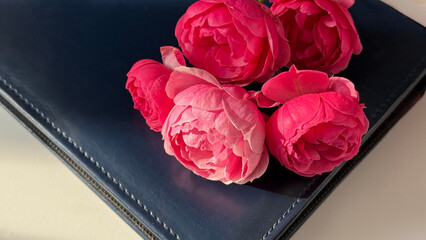 Dark blue leather notebook with pink roses on a light background. Perfect for lifestyle storytelling, writing inspiration, creative, and romantic concepts.