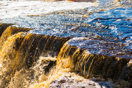Close-up of fast flowing water over stone ledge in waterfall
