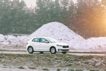 Small white vehicle rides country road
