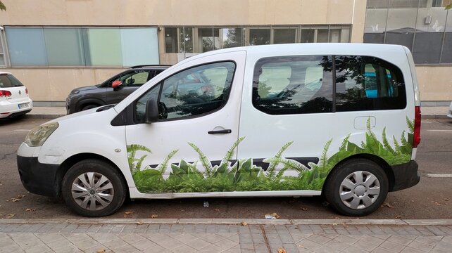 Vista lateral de una furgoneta con decoraci&oacute;n de plantas verdes aparcada en una calle de Madrid, Espa&ntilde;a