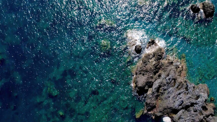 Vibrant Blue Ocean Water Surrounds Rocky Shoreline in a Tropical Setting