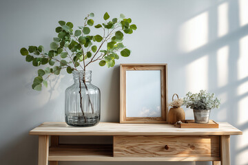A minimalist interior in soft pastel tones, featuring a single green branch in a glass vase on a light wooden table