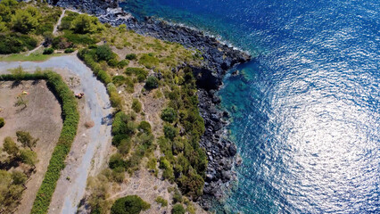 Coastal Landscape With Rocky Shore and Clear Blue Water During Midday Near a Winding Path