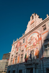 Palazzo San Giorgio in the city of Genoa under a blue sky and flags at half-mast