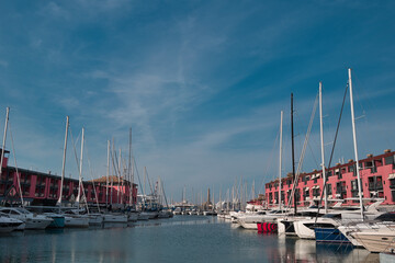 harbor with sailing ships and lighthouse of Genoa in Italy under blue sky