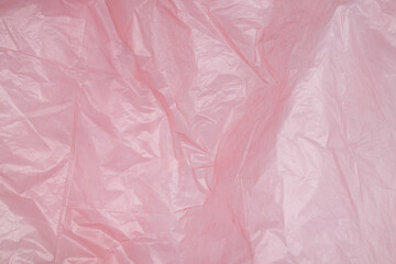 Transparent pink polyethylene background with light reflections, crumpled plastic on a white background, packaging material texture for mockup, design