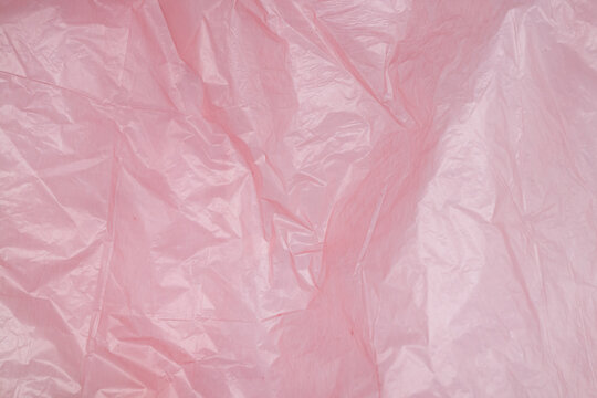 Transparent pink polyethylene background with light reflections, crumpled plastic on a white background, packaging material texture for mockup, design