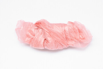 Close-up of a pink crumpled plastic bag lying on a white