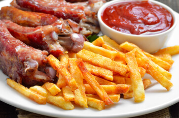 Potato fries, pork ribs and tomato sauce