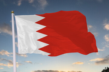 Bahrain national flag waving proudly against a bright blue sky, symbolizing unity, national pride, and cultural identity through its red field and white serrated band.