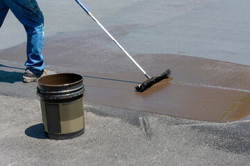 Man spreading asphalt sealer on a large home driveway