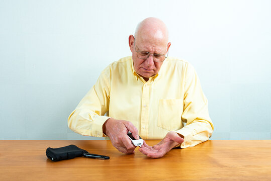 Elderly Man Checking Sugar Level With Glucose Meter At Table