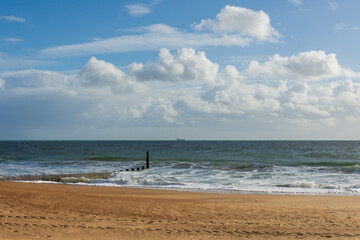 East Cliff Beach, Bournemouth, UK - October 24th 2025: View from the sandy beach of clouds over Poole Bay and a ship on the horizon.