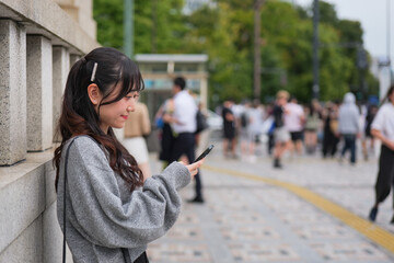 Obraz premium Young woman looking at smartphone on a sidewalk