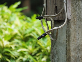 Repairing old electrical wires by wrapping black electrical tape around all four wires. This is a temporary repair that may cause danger to the user in the long run. Wires installed on utility poles.
