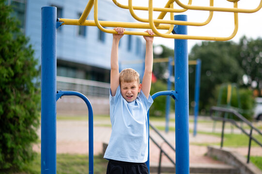 Blond boy hanging on monkey bars at outdoor playground