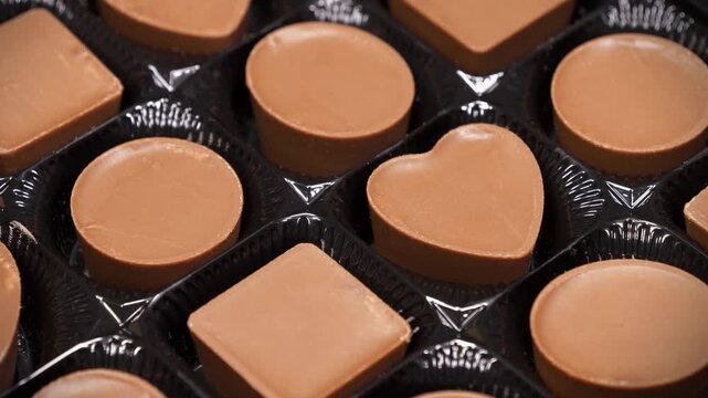 Valentines Day Gift. Candies are round, square and heart-shaped. Chocolate candies in a packaging. Delicious chocolate candy with of different forms, including heart-shaped ones