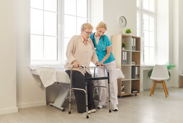 Nurse helping senior patient safe walking, elderly patient using walker to stand with support of...