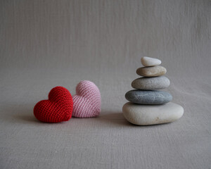 Handmade knitted hearts and balanced zen stones create a sense of love, harmony, and peaceful wellness background