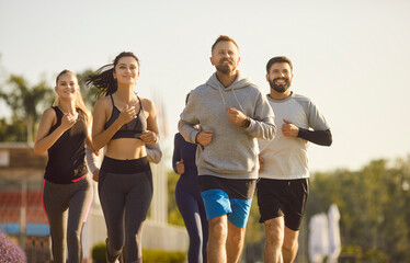 Sporty group of happy friends, people running together outdoors, moving participating in fitness activity, health breathing in fresh air, dynamic exercise, active healthy lifestyle positive teamwork