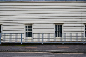 White wall with bottom windows and fence separating street
