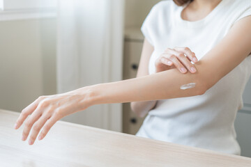 Health skin care, beauty asian young woman, girl hand applying, putting moisturizer on her arm, elbow after shower bath in room at home. Skin body cream moisturizing lotion, routine in morning.