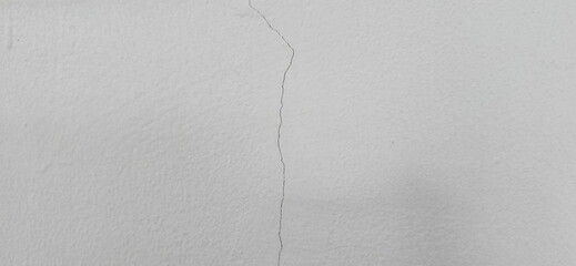 The grey wall has cracks. External cracks in the building. Cracks on the wall are straight lines from the vertical direction. Building problems and solutions. Damage from subsidence, vibration.
