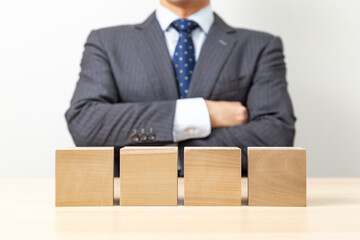 腕組みをするビジネスマンと無地のブロック