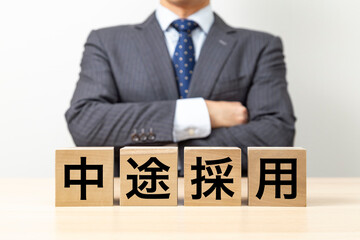 「中途採用」と書かれたブロックと腕組みをするビジネスマン