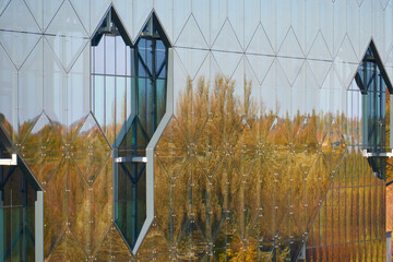 widok na współczesny budynek  z odbiciem lasu w fasadzie