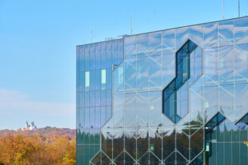widok na wsp&oacute;łczesny budynek  z odbiciem lasu w fasadzie