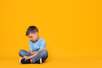 Upset little boy on orange background. Space for text