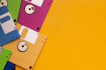 Colorful retro floppy disks piled on a bright yellow back