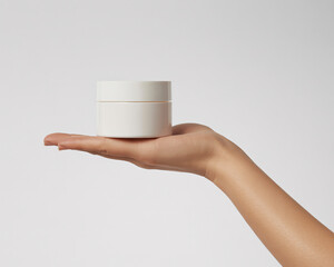 Elegant hand gently holds a pristine white cosmetic jar, showcasing modern skincare luxury and purity for beauty brands