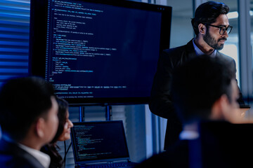 Fototapeta premium A focused male AI solutions architect in a futuristic control hub debates generative AI applications collaborating on a complex machine learning model with his team under atmospheric blue lighting.