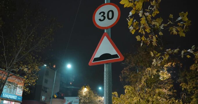 Sign for a hump and a speed limit of 30 at night time