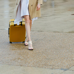 A stylish woman with a bright yellow suitcase.