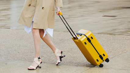 A stylish woman with a bright yellow suitcase.