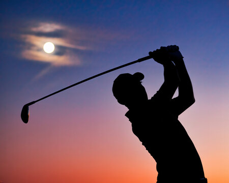 Silhouette golfer swinging club under stunning sunset sky with full moon, perfect for sports and leisure concepts