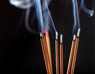 close up of burning incense sticks on a black backdrop