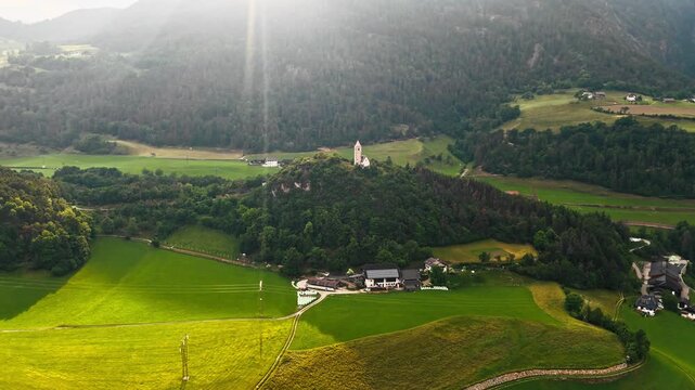 Chiesa di Santa Verena under sunset conditions in Dolomites, aerial view. South Tyrol landscape with a church landmark